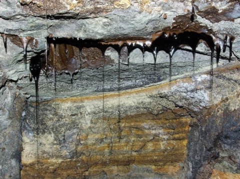 Stalactites de bitumes dégoulinant du plafond d'une galerie